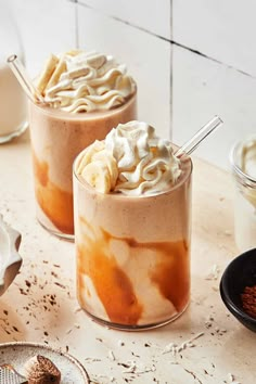 two desserts with whipped cream and cinnamon on the top are sitting on a table