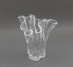 three clear glass vases sitting side by side on a gray surface, one with curved handles