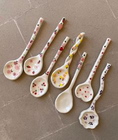 six spoons with flowers painted on them are lined up