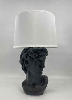 a black bust lamp with a white shade on it