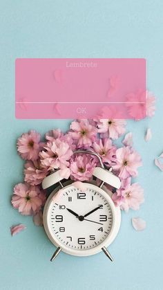 an alarm clock surrounded by pink flowers on a blue background