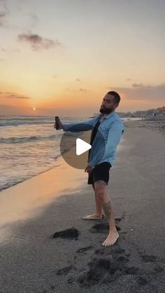 a man standing on top of a sandy beach next to the ocean at sunset with footprints in the sand