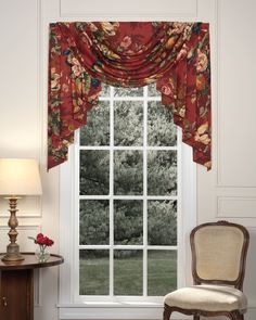 a chair sitting in front of a window with a red flowered valance on it