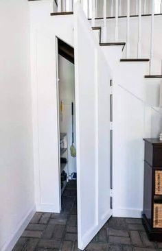 an open door leading to a room with white walls and wooden stairs in the background