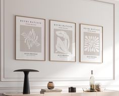 three framed art prints hang on the wall above a buffet table in a white room