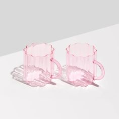 two pink glass mugs sitting next to each other