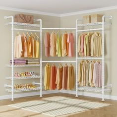 an organized closet with white shelving and lots of clothes hanging on the racks in it