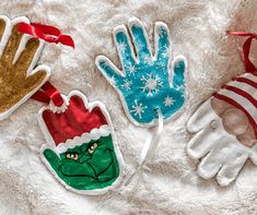 three handprinted christmas ornaments on a white blanket