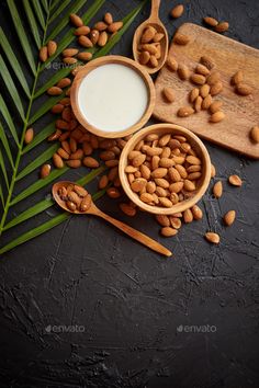 almonds and milk in wooden bowls with palm leaves on black background - stock photo - images