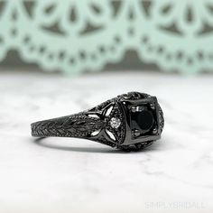 M A T E R I A L S ~ Solid Sterling Silver ~ Black Rhodium S T O N E S Cruelty Free ~ Simulated Black Diamond ~ Center Stone : 0.45ct ~Side White Diamonds: 0.12ct D I M E N S I O N S ~ Band: 3.00mm ~ Setting: 5.75mm Height 9.00mm Width R I N G C A R E ~ Simple instructions to care for the ring is not expose your jewelry to chemicals like bleach, chlorine, hairspray, to avoid chemical reactions or breakdown of materials. (Just as you would with any jewelry) ~ Try not wear your jewelry in the showe Classic Black Rings For Anniversary, Classic Black Jewelry With Center Stone, Black Diamond Ring With Accent Stones, Formal Black Rings With Accent Stones, Formal Black Rings With Black Diamonds, Classic Black Ring With Halo Setting, Black Diamond Ring With Accent Stones For Formal Occasions, Classic Black Rings With Accent Stones, Formal Black Diamond Ring With Accent Stones