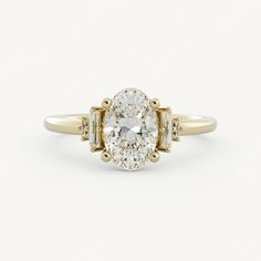 an oval diamond engagement ring with three baguets in yellow gold and white diamonds