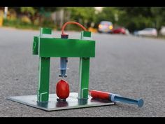 a small toy machine sitting on the ground next to a red ball and screwdriver