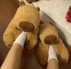 two brown teddy bears sitting next to each other on the floor with their legs wrapped around them