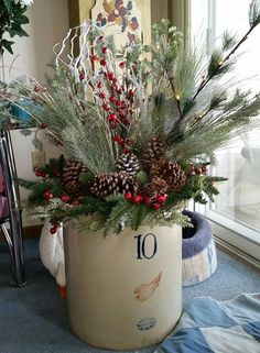 a potted plant with pine cones, berries and evergreens in it sitting on a bed