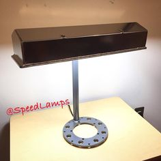 a desk lamp sitting on top of a wooden table next to a sign that says speed lamps