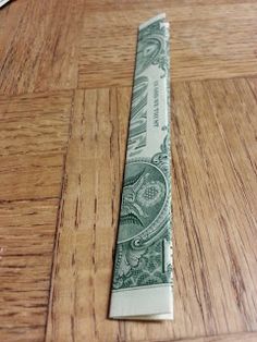 a rolled up dollar bill sitting on top of a wooden table