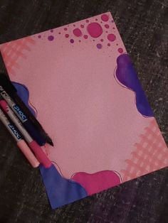 two pens are sitting on top of a piece of paper with pink and purple designs