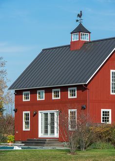 a red barn with white windows and a black roof