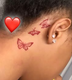 a woman's back neck with butterflies on it and a red heart behind her ear