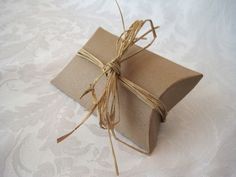 a wrapped gift box sitting on top of a white tablecloth covered table cloth with twine tied around it