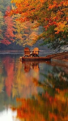 two chairs sitting on the edge of a lake