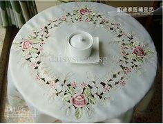 a white table topped with a cup and saucer on top of a cloth covered table