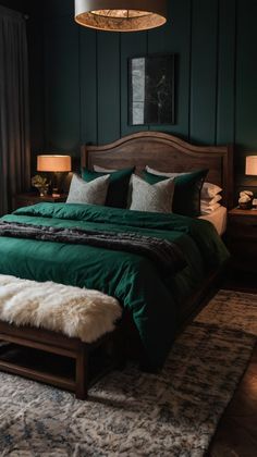 a bed with green sheets and pillows in a dark room next to two lamps on either side of the bed