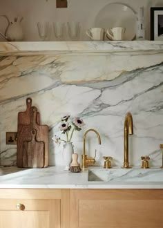 a kitchen with marble counter tops and gold faucets on the sink, next to cutting board