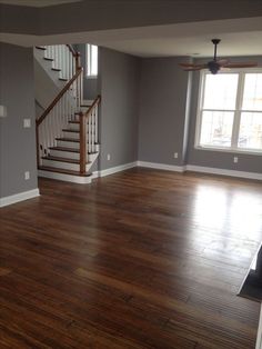 an empty living room with hard wood floors and white railings on the second floor