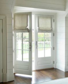 the inside of a house with two white doors and windows that have blinds on them