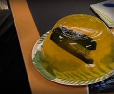 a yellow plate with a black object on it sitting on a desk next to a book