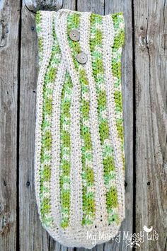 a green and white crocheted bag sitting on top of a wooden table