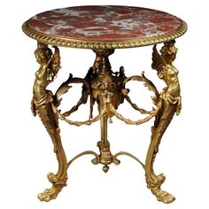 an ornately decorated table with two cherubs on the base and a red marble top