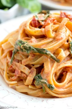 pasta with tomato sauce and spinach on a white plate, ready to be eaten