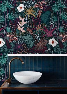 a bowl sink sitting on top of a counter next to a wall covered in plants