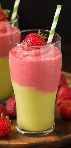 a smoothie in a glass with strawberries on the side and another one behind it