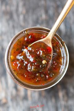 a spoon full of sauce sitting on top of a wooden table