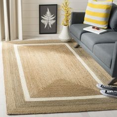 a living room with a gray couch and yellow striped pillows on the floor, along with an area rug