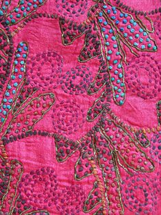 a close up view of a pink fabric with flowers and leaves in the center on it