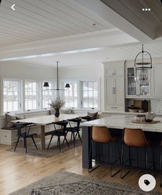 an open kitchen and dining room with white walls, wood flooring and large windows