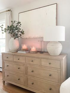 a dresser with candles on top and a mirror above it in a living room area