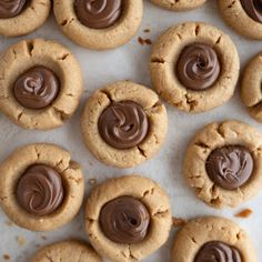 peanut butter cookies with chocolate frosting arranged on a baking sheet lined with parchment paper