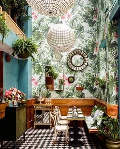 the interior of a restaurant decorated with tropical wallpaper and potted plants on the walls