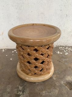 a round wooden table sitting on top of a cement floor