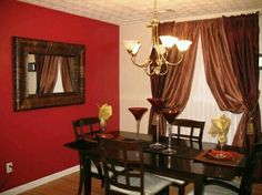 a dinning room with red walls and curtains