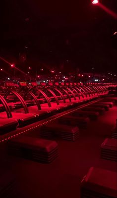 rows of seats in an empty stadium with red lights on them at night or day