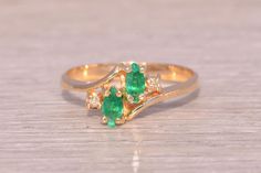 This stunning piece, known as The Emerald Harmony, features two captivating marquise cut natural emeralds at its center. The emeralds are elegantly set in 14 karat yellow gold and are flanked by four round brilliant cut natural diamonds, adding a touch of sparkle and enhancing the ring's elegance. The ring is crafted in 14 karat yellow gold and is currently a finger size 6.25 but can be adjusted to any finger size for an additional charge upon request, ensuring a perfect fit. Love this piece, but don't have the money to spend right now?  We offer FREE layaway on every item in our shop.  With just 20% down, take one full year (interest-free) to pay off your new jewelry!  There are no hidden fees or charges, ever.  For more information on our layaway policy, please contact us. Each piece has Elegant Marquise Emerald Ring, Formal Green Marquise Emerald Ring, Green Marquise Emerald Ring For Anniversary, Marquise Emerald Ring For Formal Occasions In May, Elegant Green Marquise Cut Emerald Ring, Elegant Marquise Cut Emerald Ring, Formal Marquise Cut Emerald Ring, Marquise Emerald Ring For Anniversary, Emerald Ring Vintage