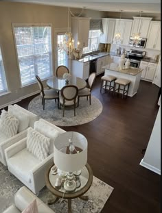 an aerial view of a living room and dining room with hardwood floors, white furniture, and chandelier