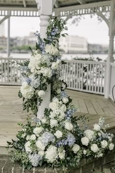 white and blue flowers are arranged on the corner of a gazebo