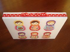 a white box with red polka dots and dolls on the front, sitting on a wooden table